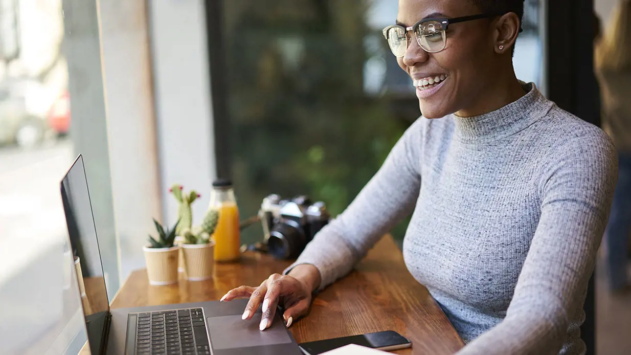 A smiling woman using a laptop.