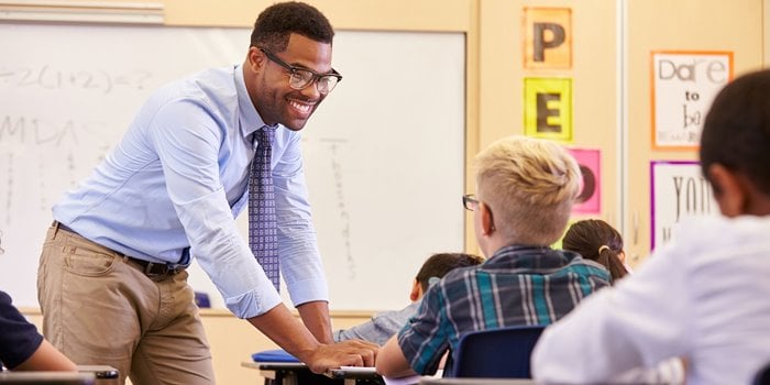 Teacher bending down to help student at a desk