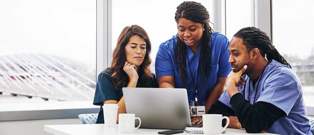Group of healthcare professionals looking at a laptop screen