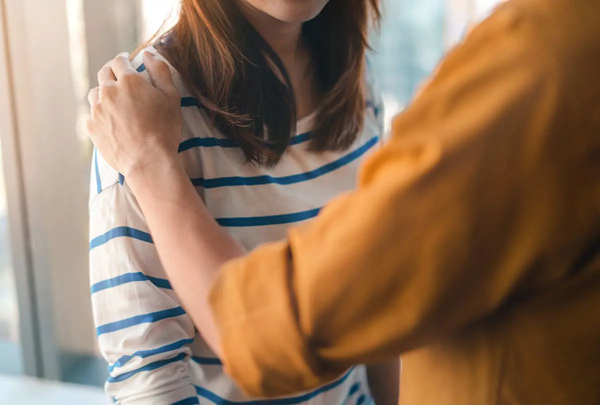 A woman hugs another woman, symbolizing friendship and emotional connection between them.