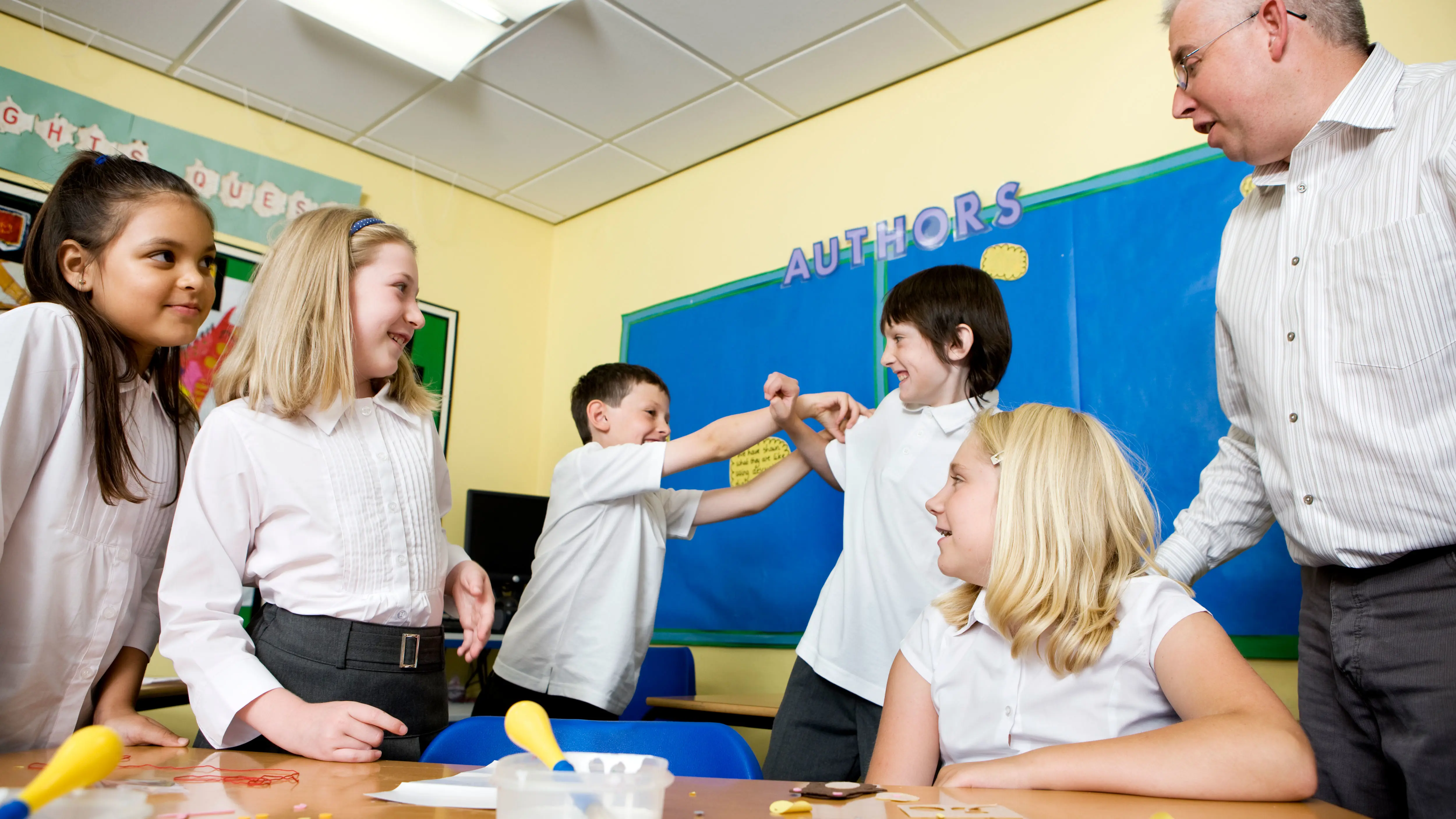 A teacher talking to 4 students within a classroom