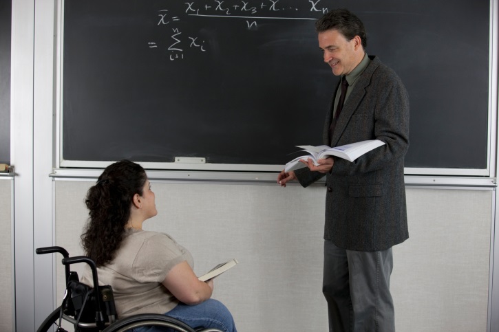 Teacher and student in wheelchair in front of blackboard