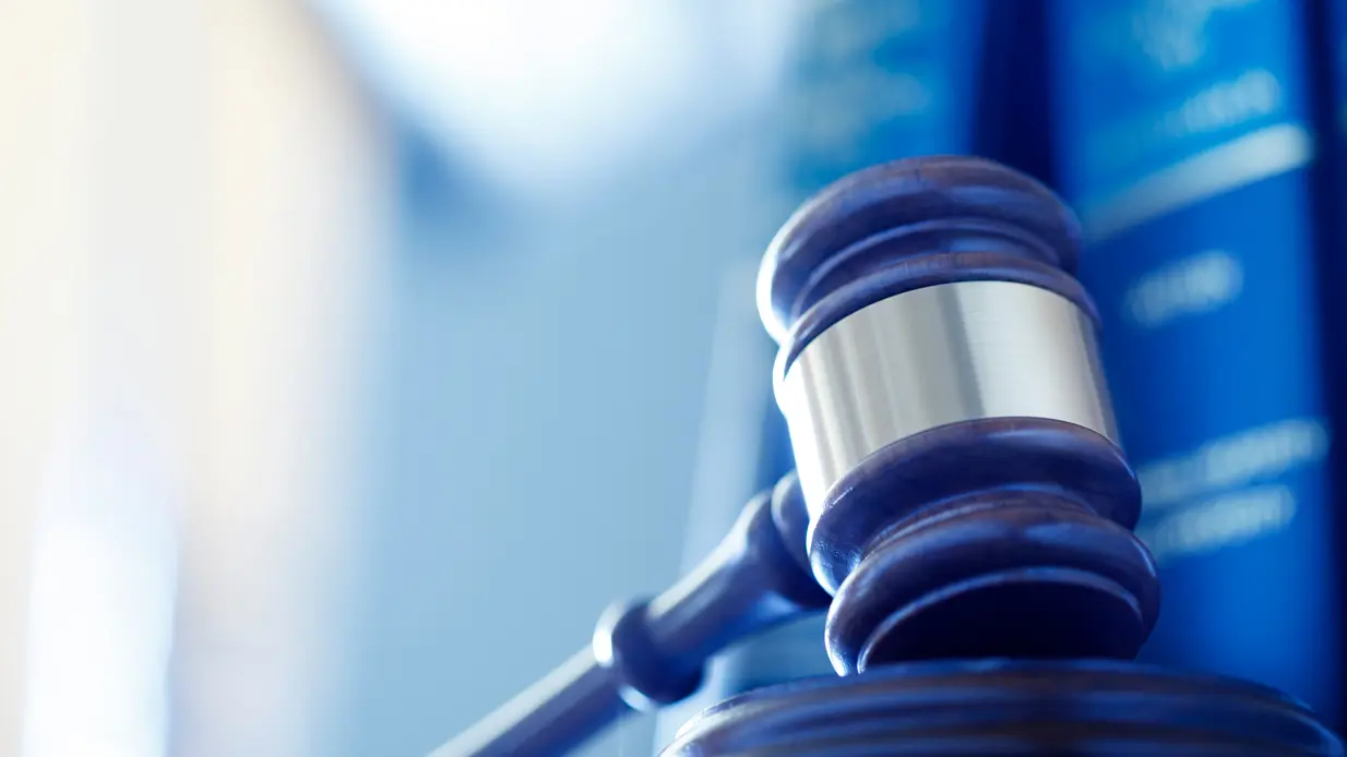 A gavel rests on a stack of law books, symbolizing the principles of law and justice in a legal context.