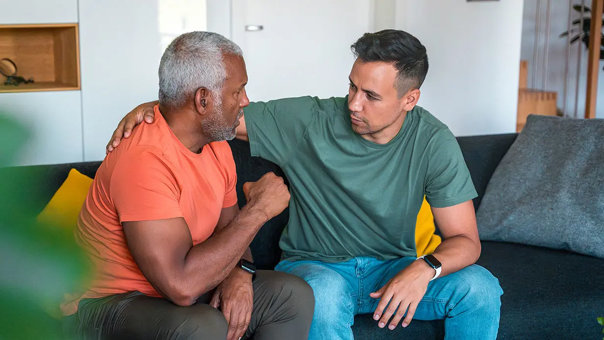 Two men engaged in conversation while seated on a comfortable couch in ...