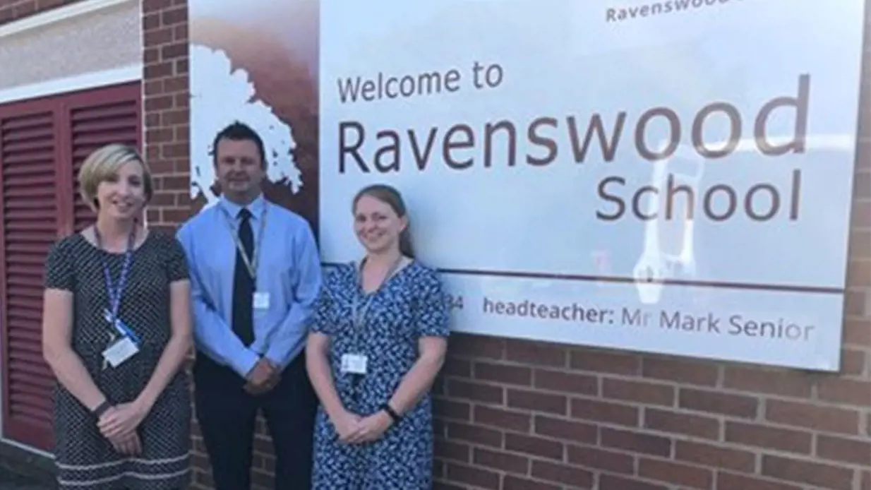 Teachers outside of the Ravenswood School Sign