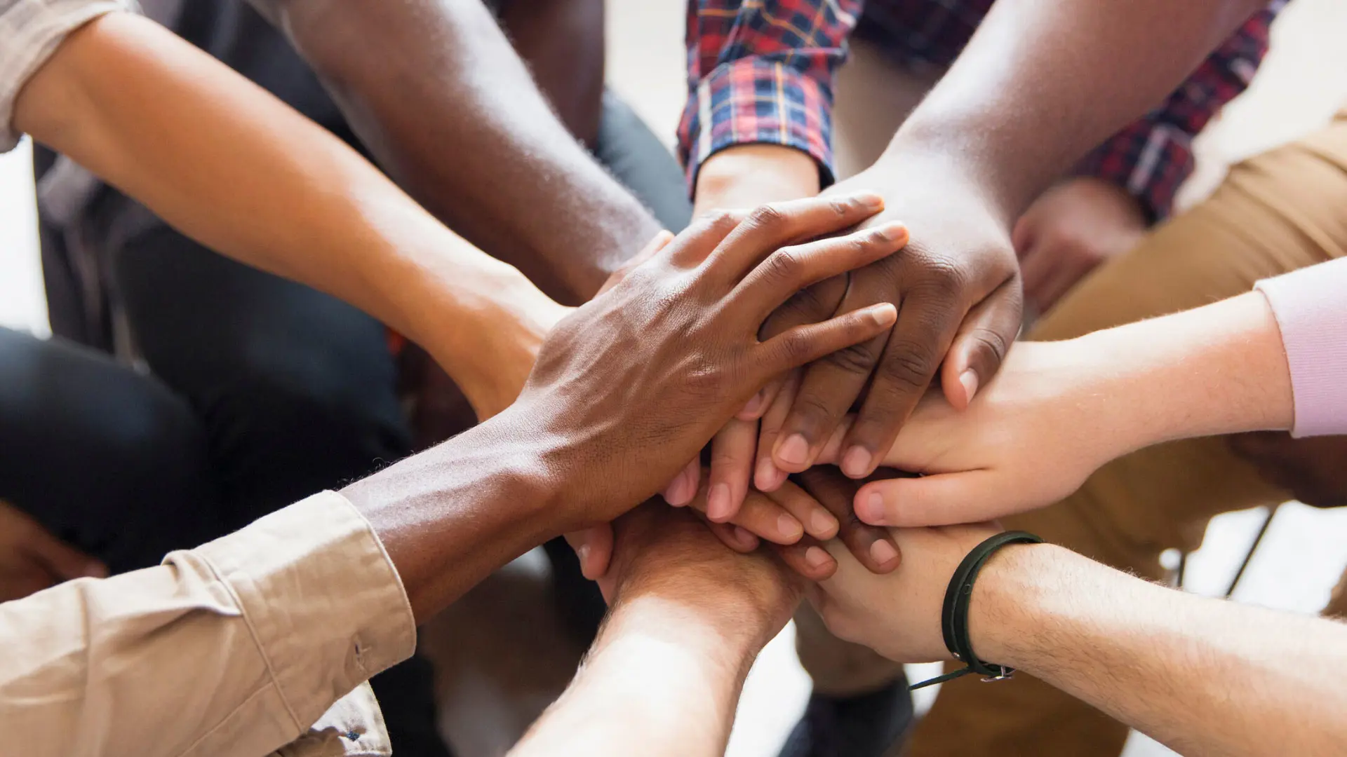 A group of people sitting in a circle putting their hands together