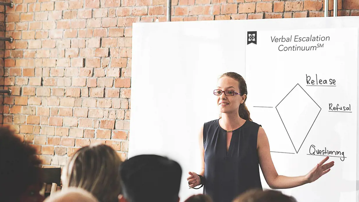 Woman standing at a flip chart talking to a training class