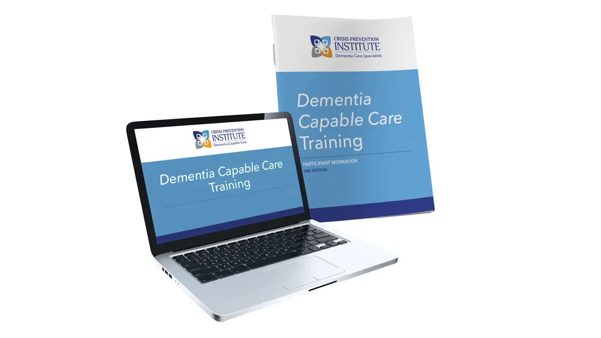 A laptop and a workbook with the name of the training programme: Dementia capable care