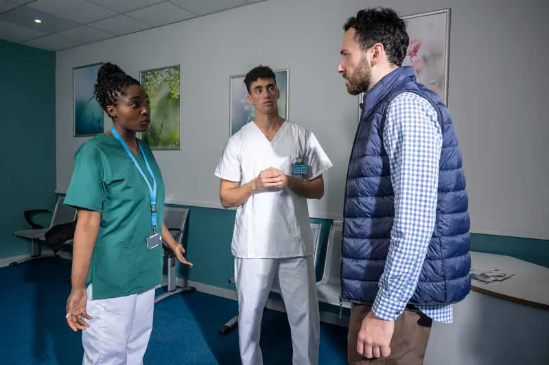 Infirmier et aide soignante en conversation avec un patient