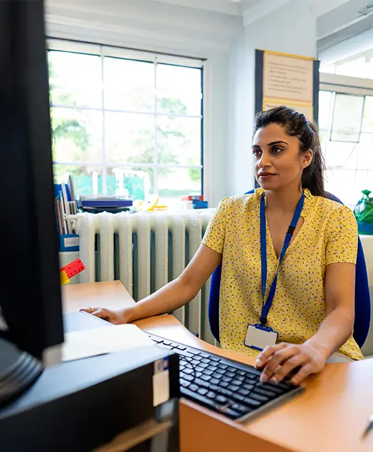 A woman seated at a desk, focused on her computer screen, engaged in work or study.