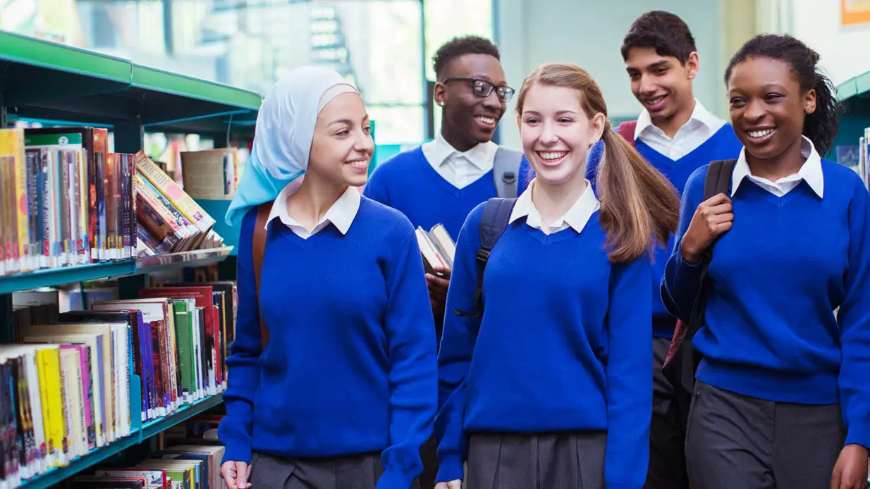 A group of smiling students wearing blue sweaters. 