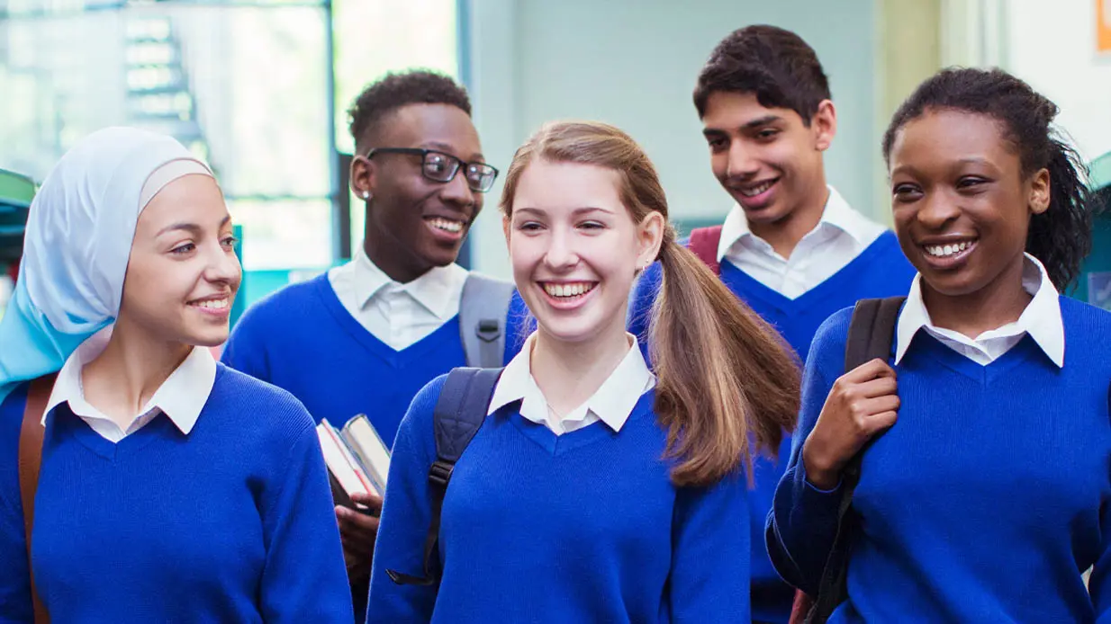A group of smiling students wearing blue sweaters.