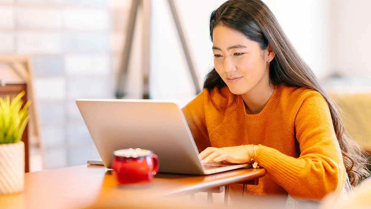 A smiling woman using a laptop.