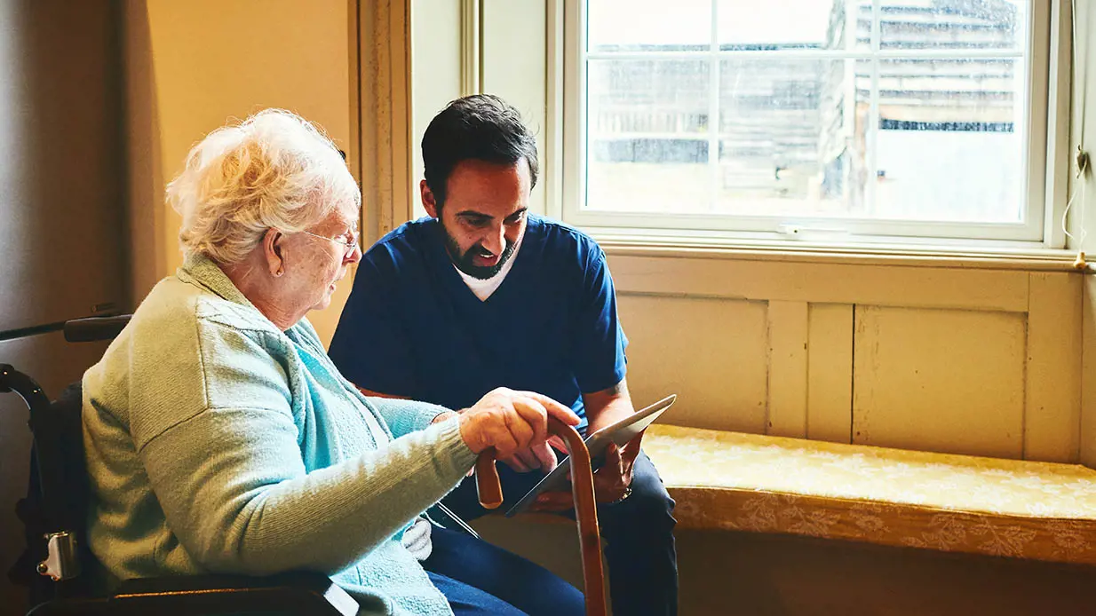 A medical professional reading something to an elderly patient. 