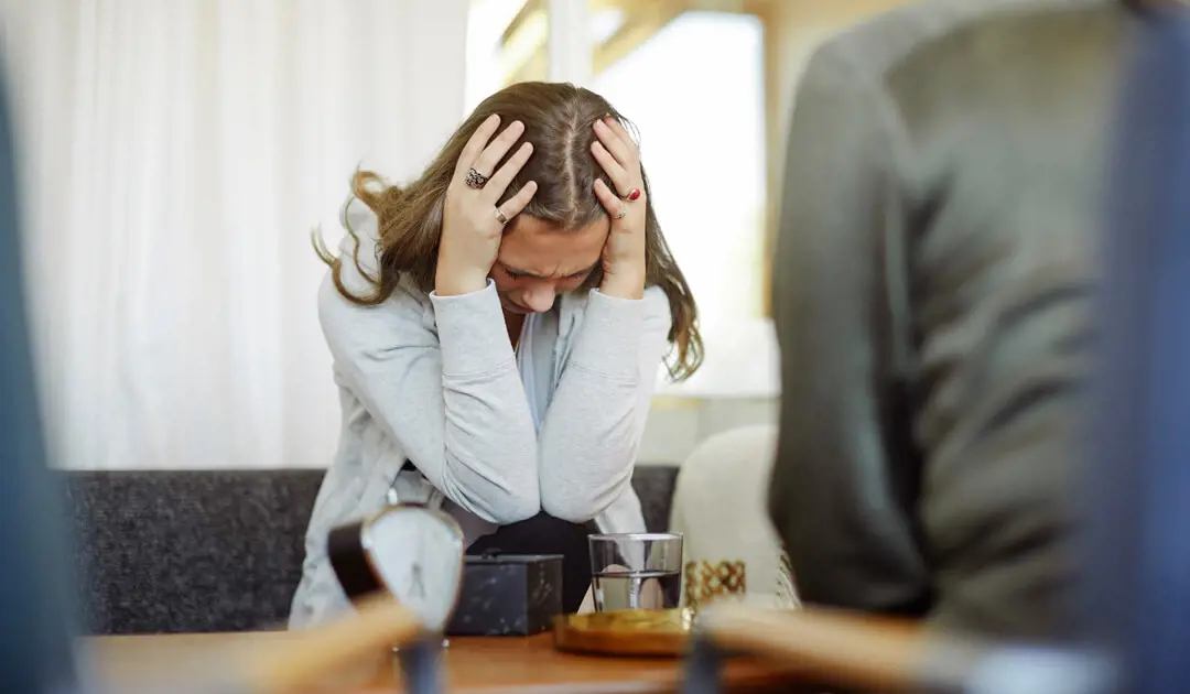 Woman sitting on a step with her head in hands looking stressed