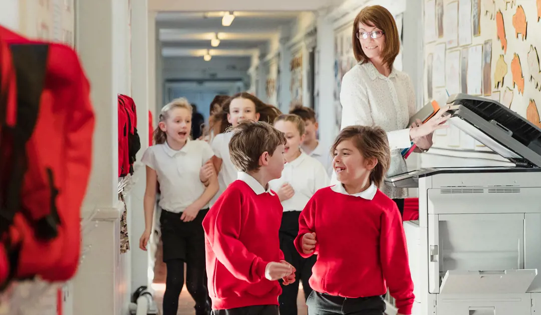 Teacher with a group of students in a corridor in red uniforms