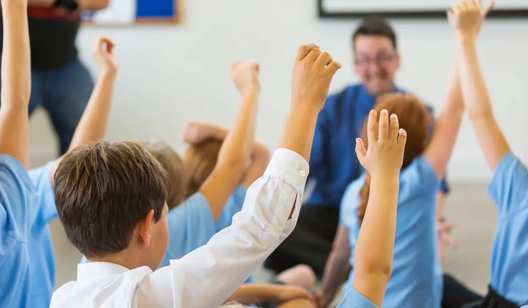 Classroom of students raising hands to answer a question