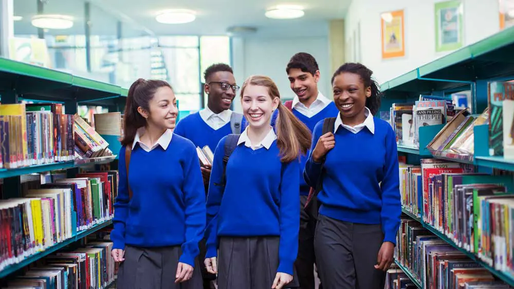 Five school children walking in a libary