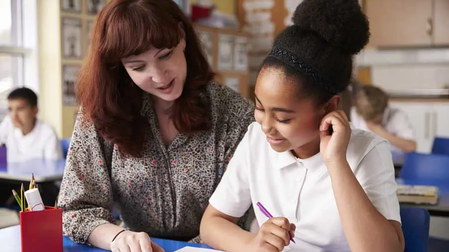 Primary teacher explaining something to a student.