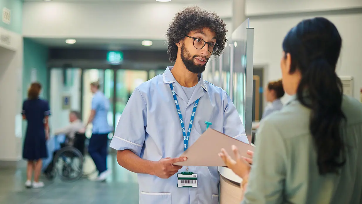 A man wearing a lanyard talking to someone.