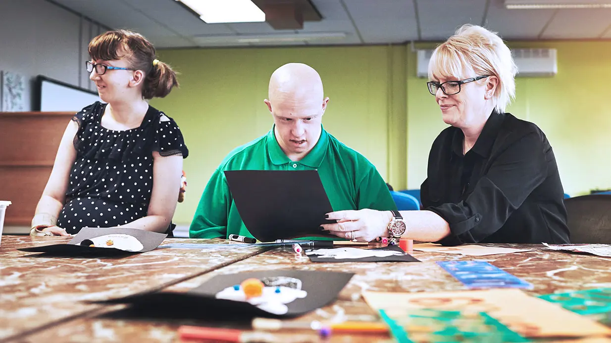 A professional works with two people with special needs. 