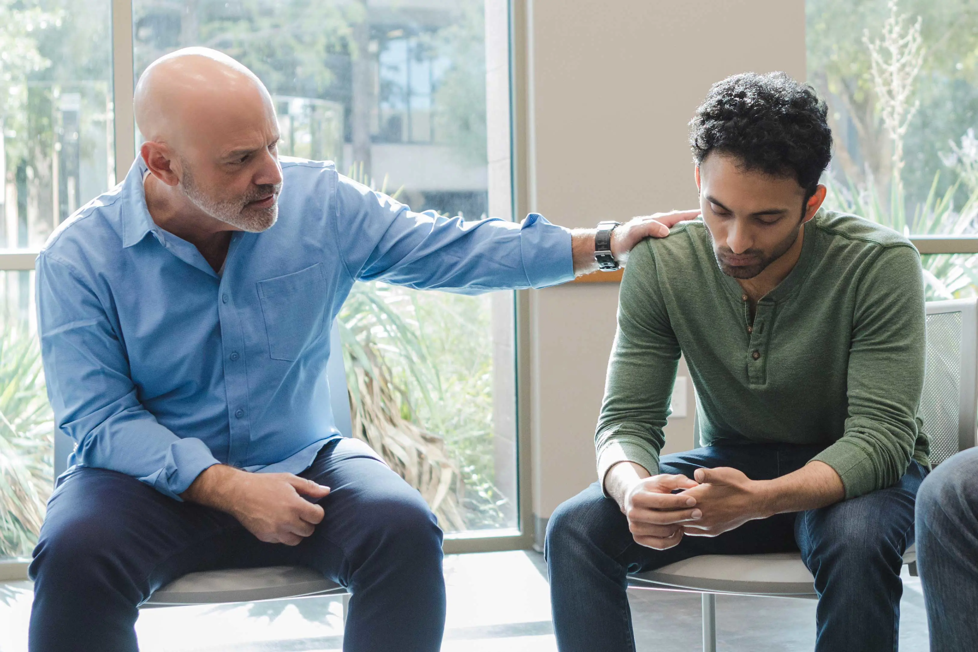 A man puts his hand on another man's shoulders in an effort to comfort.