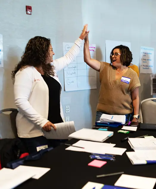 Two women high fiving each other at a CPI training.