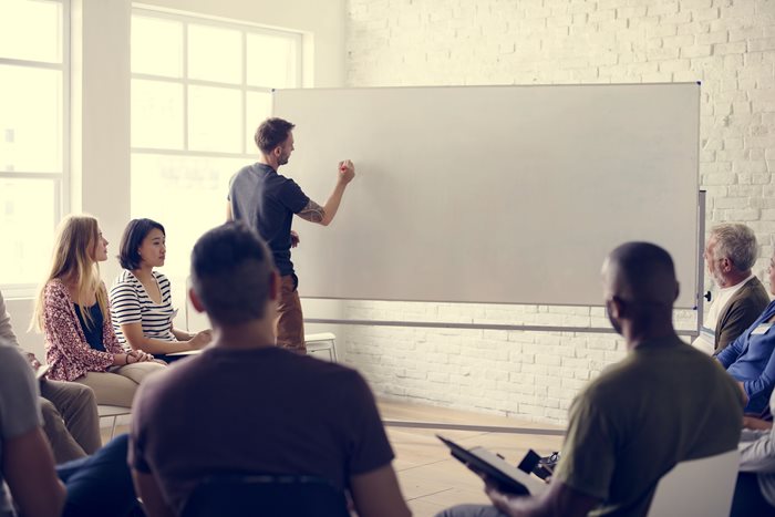 Man at a whiteboard writing during training