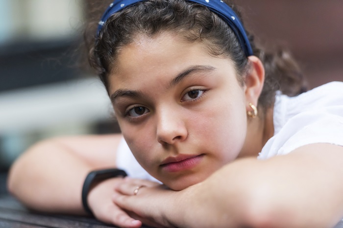 Girl with blue headband and brown hair staring at camera