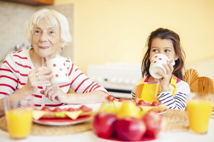 Grandmother with grand daughter eating at a table