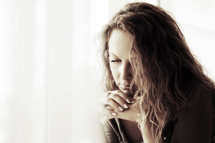 Pensive woman with hands on chin sepia photo